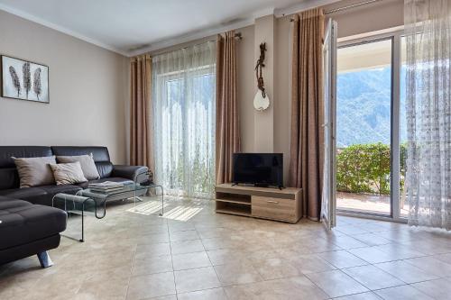un salon avec un canapé et une télévision sur une table dans l'établissement GREEN HILL 2 Apartmani with POOL, à Gornji Orahovac