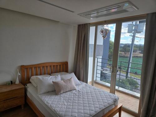 a bedroom with a bed and a balcony at The Stay Christmas in Jeju