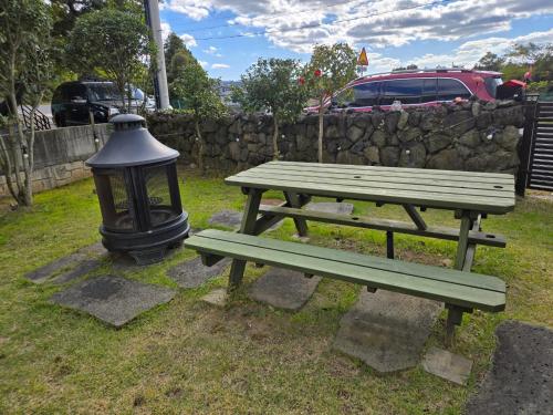 a green picnic table and a light next to a stone wall at The Stay Christmas in Jeju