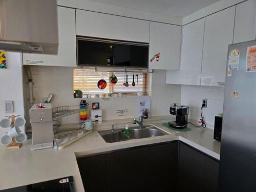 a kitchen with white cabinets and a sink at The Stay Christmas in Jeju