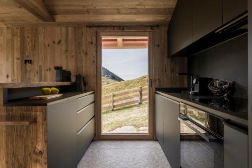a kitchen with a view of a hill through a window at Stay COOPER I DIAMANTIDI Lodge - Modern Mountain Chalet in the Dolomites in Obereggen