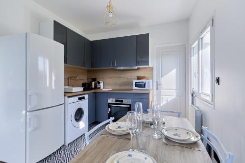 une cuisine avec une table et un réfrigérateur blanc dans l'établissement Appartement Évasion Normande - Welkeys, à Cabourg