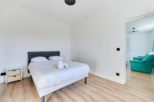 - une chambre blanche avec un lit et une chaise bleue dans l'établissement Appartement Évasion Normande - Welkeys, à Cabourg