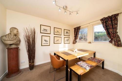 a dining room with a table and a statue at Milton of Tullypowrie Cottage in Pitlochry