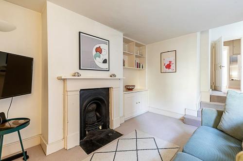 a living room with a fireplace and a blue couch at Cosy Flat in Battersea Park in London