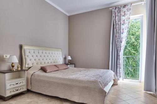a white bedroom with a bed and a window at GREEN HILL 2 Apartmani with POOL in Gornji Orahovac
