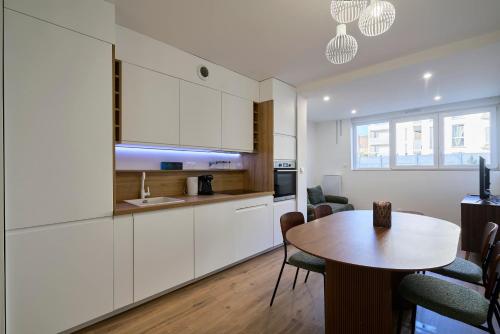 une cuisine avec des armoires blanches et une table avec des chaises dans l'établissement T2 chic et contemporain au RDC - proche de Lille, à Mons-en-Baroeul