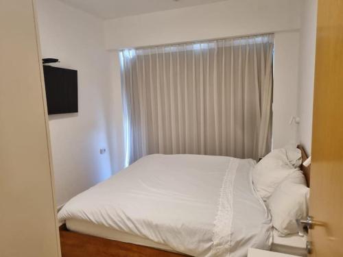 a white bed in a room with a window at חדר שינה וסלון ומרפסת נוף לים in Herzliyya B