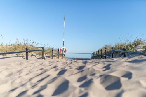 a boardwalk leading to the beach with the ocean in the background at Köpmans Boutique Hotel & Bistro in Höganäs