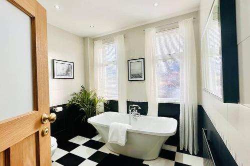 a bathroom with a white tub and black and white checkered floor at Stunning Coastal Retreat Whitley Bay Sleeps 9 in Whitley Bay
