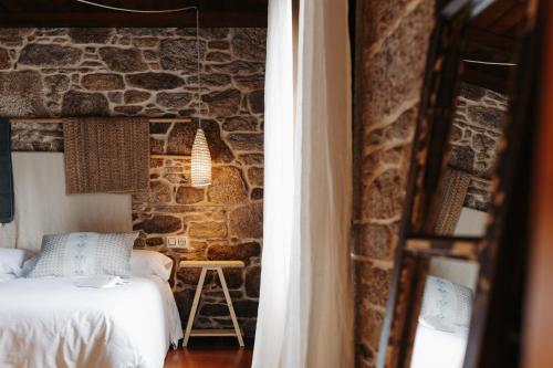 a bedroom with a bed and a stone wall at Arrueiro in Laxe