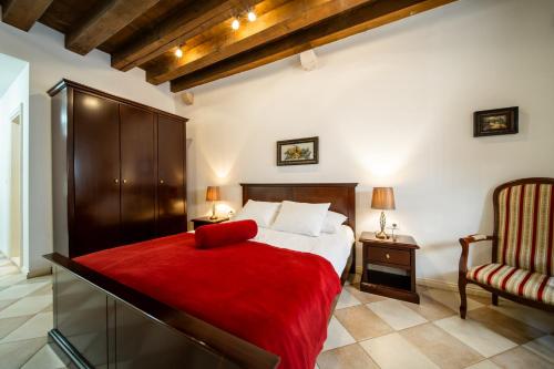 a bedroom with a red bed and a chair at SUNce Palace Apartments with free offsite parking in Dubrovnik