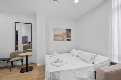 a white room with a bed and a table and a mirror at Enjoy Apartments and Suites in Zagreb