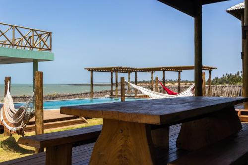 a picnic table and hammocks on a deck with the beach at Vila Insular - Beira-mar - 3 casas p/ até 36 in Cajueiro