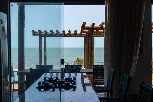 a dining room with a table and a view of the ocean at Vila Insular - Beira-mar - 3 casas p/ até 36 in Cajueiro