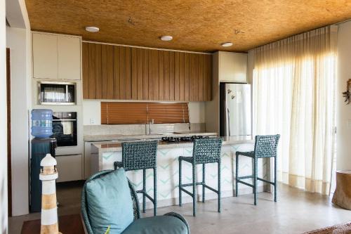 a kitchen with a counter with chairs and a island at Vila Insular - Beira-mar - 3 casas p/ até 36 in Cajueiro