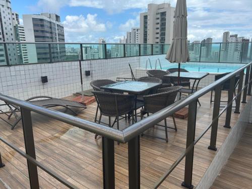 a balcony with tables and chairs and a swimming pool at Flat Boa Viagem -500 m praia - Golden Style in Recife
