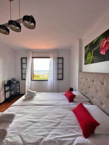 a bedroom with a large white bed with red pillows at Casa Valhalla in Funchal