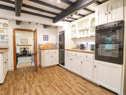 a large kitchen with white cabinets and wooden floors at Cherry Tree Cottage in Nottingham