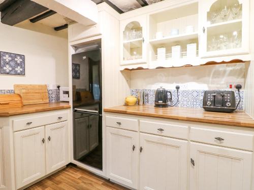 a kitchen with white cabinets and a counter top at Cherry Tree Cottage in Nottingham