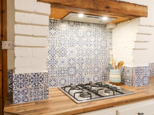 a kitchen with blue and white tiles on the wall at Cherry Tree Cottage in Nottingham