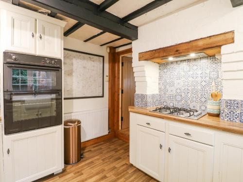 a kitchen with white cabinets and a stove top oven at Cherry Tree Cottage in Nottingham