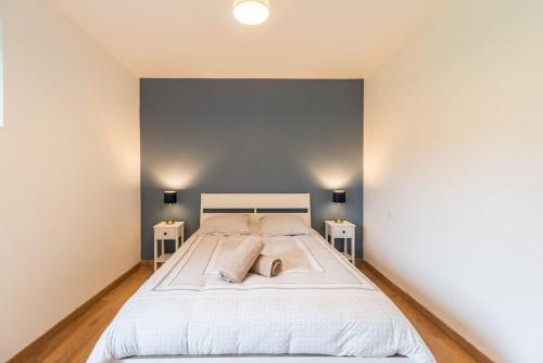 1 Schlafzimmer mit einem großen weißen Bett und 2 Nachttischen in der Unterkunft Charmante maison la Tissanderie a Saint-Carreuc in Saint-Carreuc