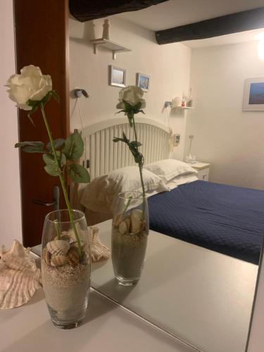two vases with flowers on a table next to a bed at CASABARBARA lerici in Lerici