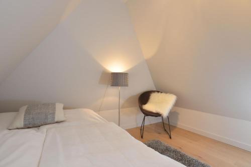 een slaapkamer met een bed en een stoel bij Witthüs 15 in Wenningstedt