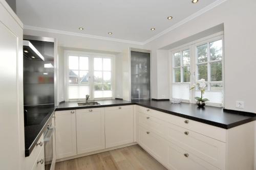 a kitchen with white cabinets and black counter tops at Sylt Hüs in Wenningstedt