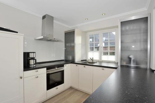 a kitchen with white cabinets and black counter tops at Sylt Hüs in Wenningstedt