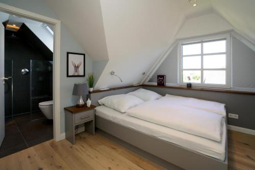a bedroom with a bed and a window and a bathroom at Ferienhaus Sylt Leev in Westerland