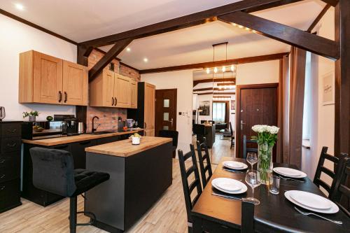 ザモシチにあるBrzozowy Dwór Apartament Iのテーブルと椅子のあるキッチンとダイニングルーム