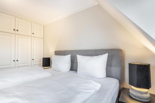 a bedroom with a bed with white sheets and pillows at Ferienhaus Lee in Munkmarsch