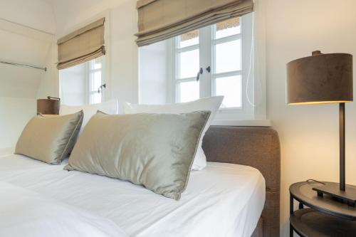 a bed with white sheets and pillows in a bedroom at NEU! Ferienhaus Sylt 44 mit eigenem Strandkorb am Strand in Wenningstedt