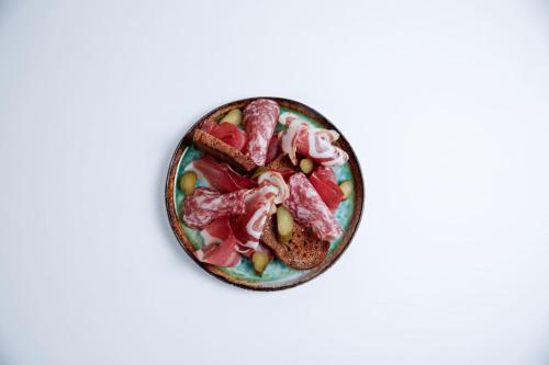 a bowl of food with meat and vegetables on a white background at Nivis Hotel in Folgarida