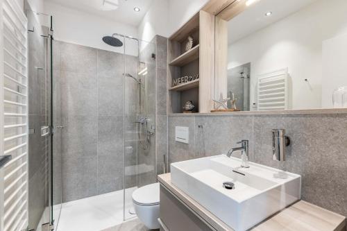 a bathroom with a sink and a shower and a toilet at Exklusives Apartment Turmkoje im Herzen Westerlands in Westerland (Sylt)