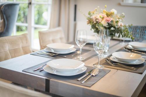 a table with plates and glasses and a vase of flowers at Ferienhaus Finoah - Leben, Luxus, Leichtigkeit hinter der Duene in Westerland Sylt in Westerland (Sylt)