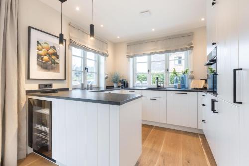 a kitchen with white cabinets and a black counter top at Ferienhaus Finoah - Leben, Luxus, Leichtigkeit hinter der Duene in Westerland Sylt in Westerland (Sylt)