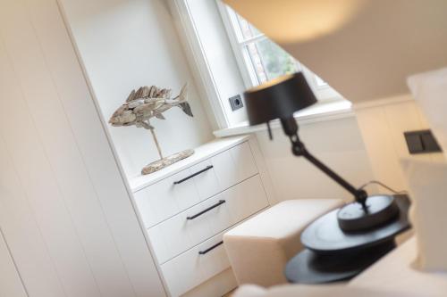 a lamp sitting on a dresser next to a window at Ferienhaus Finoah - Leben, Luxus, Leichtigkeit hinter der Duene in Westerland Sylt in Westerland (Sylt)