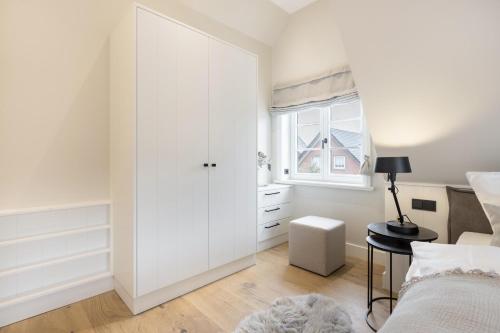 a white bedroom with a white closet and a window at Ferienhaus Finoah - Leben, Luxus, Leichtigkeit hinter der Duene in Westerland Sylt in Westerland (Sylt)