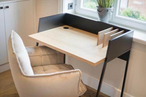 a desk with a chair next to a table at Ferienhaus Finoah - Leben, Luxus, Leichtigkeit hinter der Duene in Westerland Sylt in Westerland (Sylt)