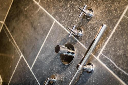a bathroom with four knobs on a tiled wall at Ferienhaus Finoah - Leben, Luxus, Leichtigkeit hinter der Duene in Westerland Sylt in Westerland (Sylt)