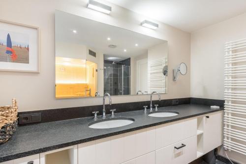 a bathroom with two sinks and a large mirror at Ferienhaus Finoah - Leben, Luxus, Leichtigkeit hinter der Duene in Westerland Sylt in Westerland (Sylt)