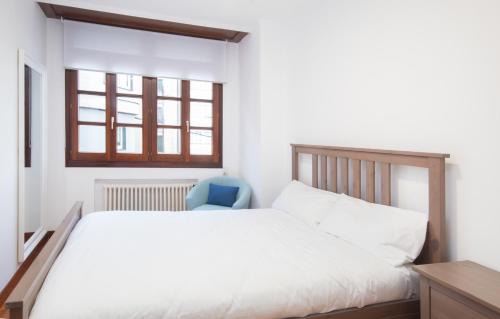 a bedroom with a white bed and a blue chair at AG Piso Valle Inclán en el centro de Carballo in Carballo