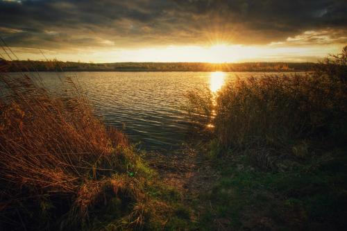 a sunset over a body of water with the sun setting at Apartament Suwałki Centrum Wesoła in Suwałki