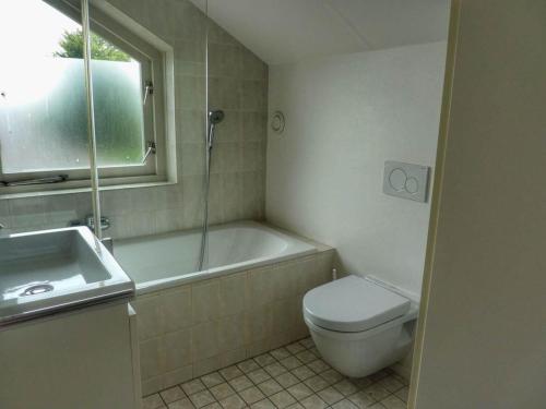 Un baño con bañera, inodoro y lavabo. en Coastal Bungalow w Garden, en Breskens
