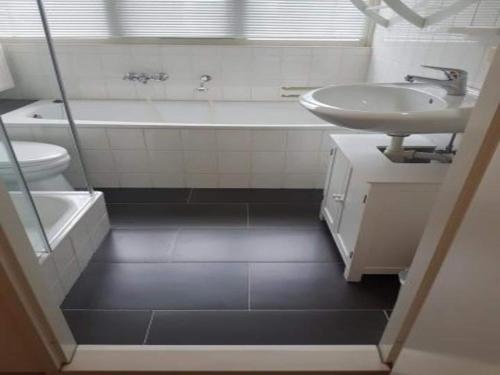 a bathroom with a sink and a tub and a toilet at Bungalow in Breskens near the Beach in Breskens