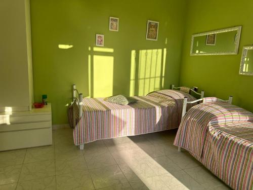 two beds in a room with green walls at Agrihome Di Alberto Giuseppe Gulotta B&B Bella Vista Appartamento Salvia in Massarosa