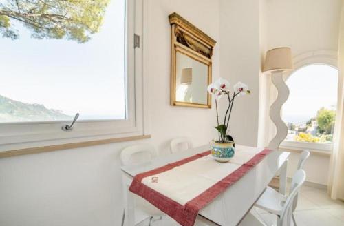 a white dining room with a table and chairs and a mirror at La Dolce Vita Ravello - Two Bedroom Apt with Sea View Terrace in Ravello